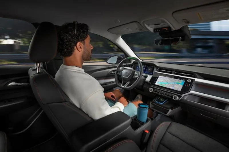 A man driving the 2027 Chevy Bolt hands-free with navigation open on the infotainment display.