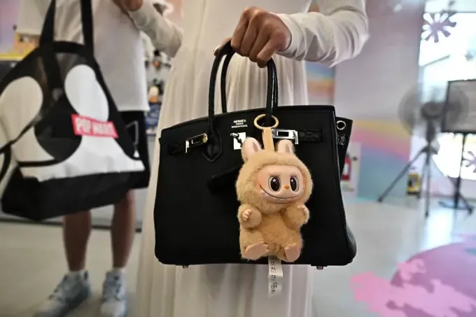 designer art toy Labubu attached to a shopper's handbag at the Pop Mart store in Siam Square in Bangkok. (