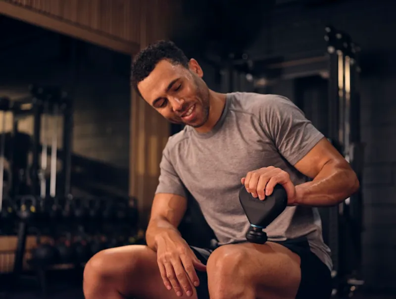 A guy using the massager at the gym.