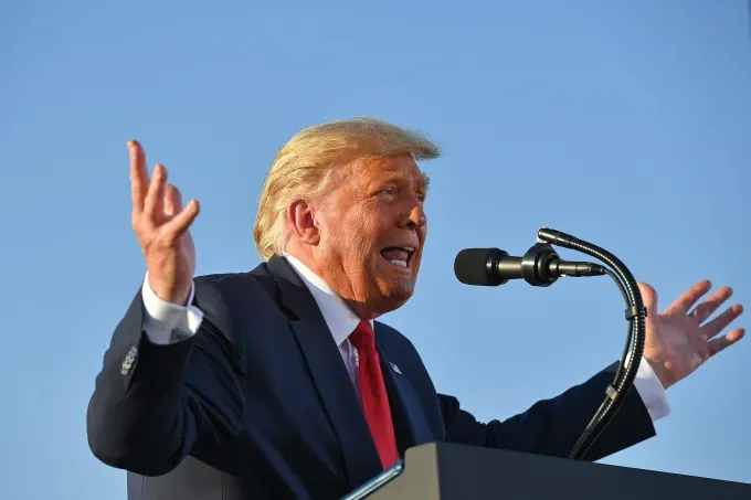 Дональд Трамп выступает с речью у микрофона на фоне неба