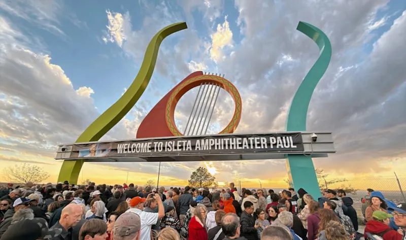 Человек держит компактную камеру Canon EOS R50 с присоединенным очень длинным объективом 70-200мм.